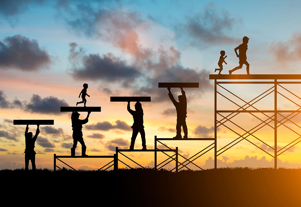 A metal sculpture of steel workers supporting running children with a sunset.