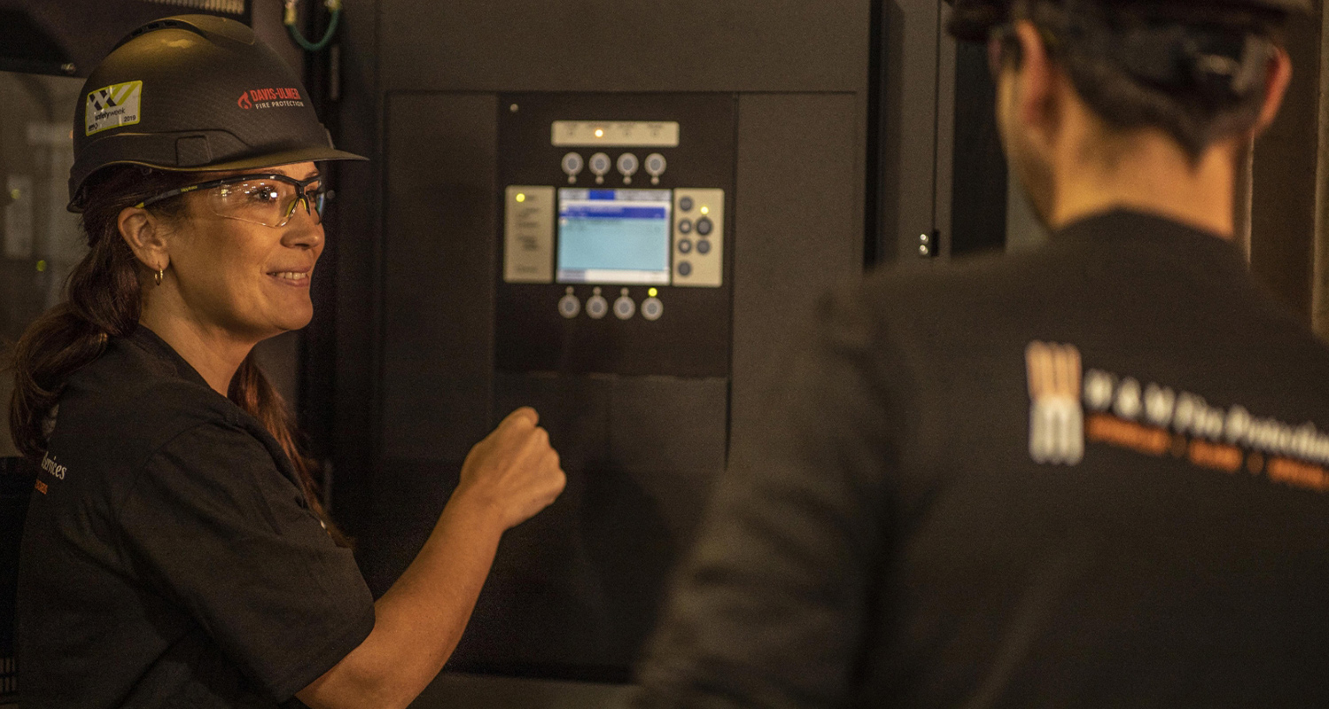 A coworker as Davis-Ulmer Fire Protection points to a system control while speaking to a coworker.