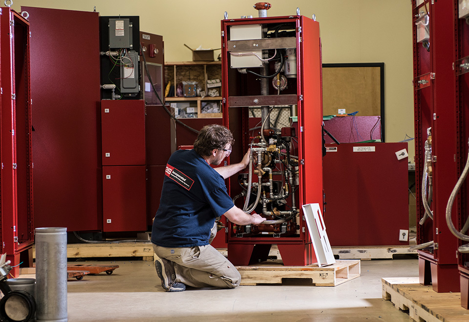 A worker wearing safety goggles is fixing a machine.