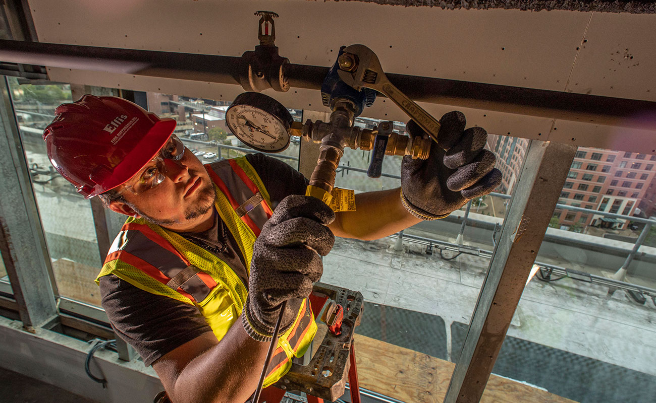 Two coworkers work side-by-side on a job site.