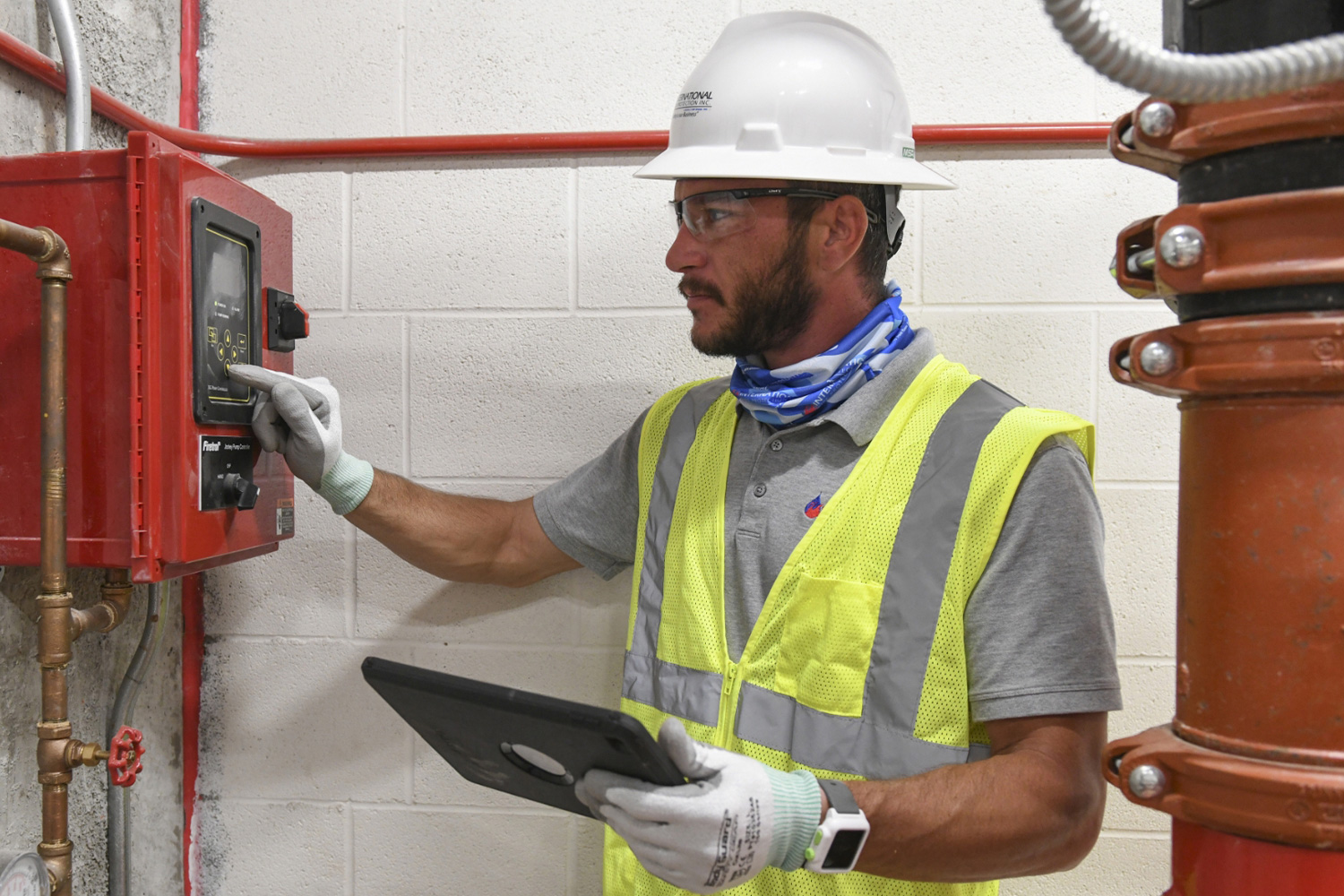 A coworker performs an inspection of fire safety equipment.